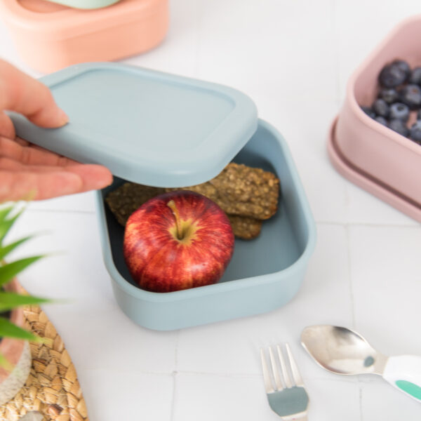 Dusty blue snack box with hand taking off lid.